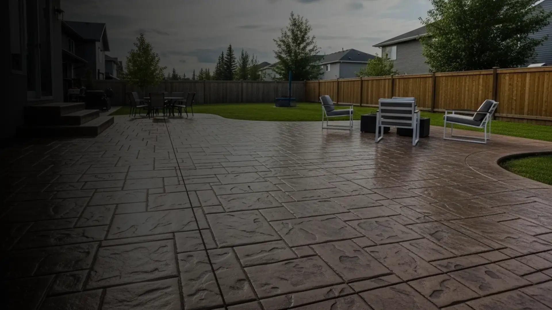 Spacious stamped concrete backyard patio with outdoor seating, built by Tenmen Construction in Calgary.